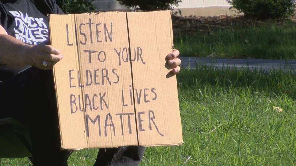 One of the protesters from to Standing Up For Racial Justice, or SURJ, held a sign calling for...