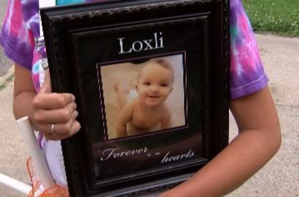 Tia Bailey carries a picture of her daughter who passed away in March of 2018. (source: Mike...