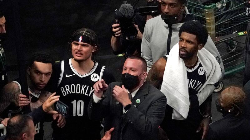 A security guard points as the Brooklyn Nets' Kyrie Irving, right with towel, and teammates...